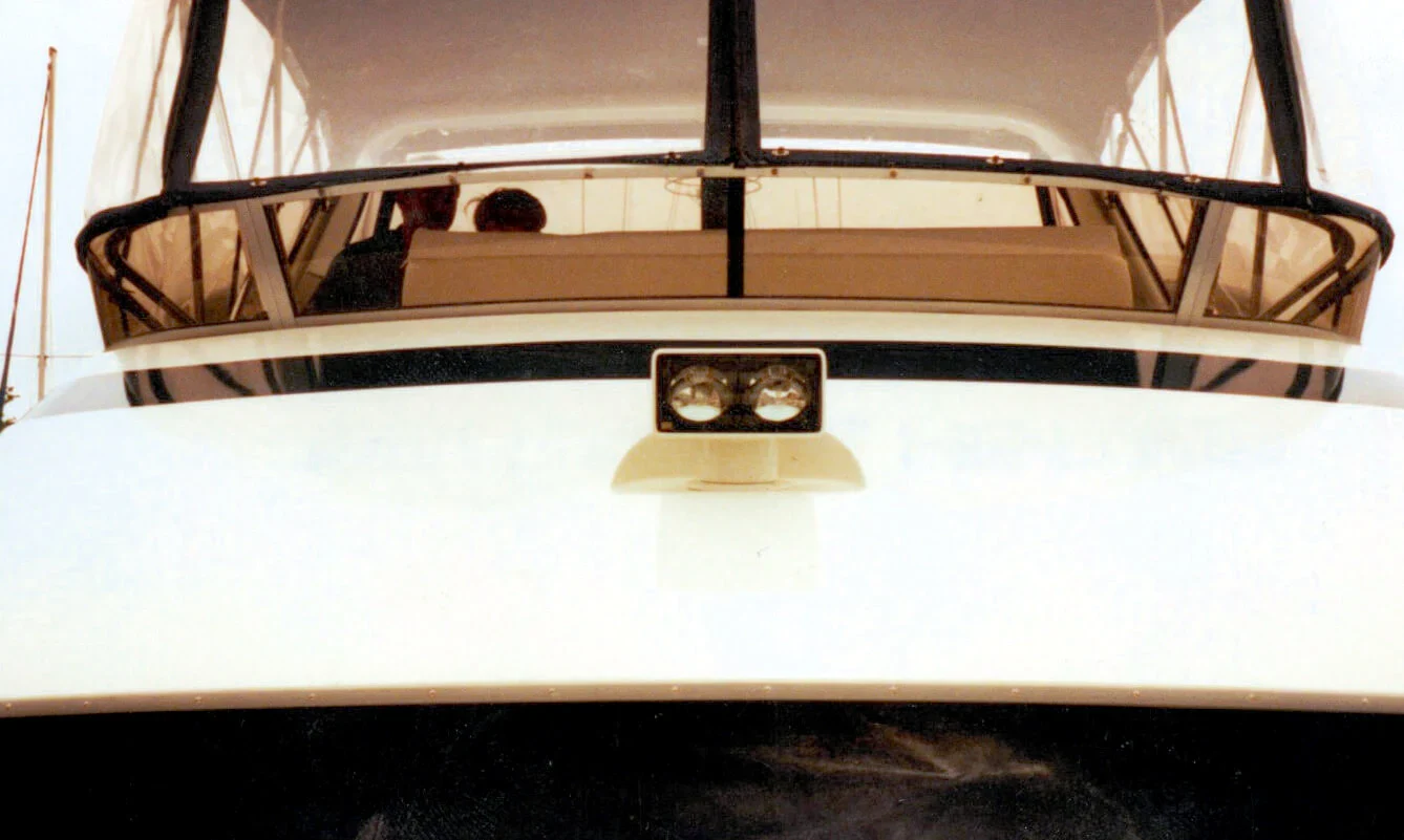 Close-up view of a boat's cabin, featuring a large windshield, control panel, and two bright lights mounted on the front.